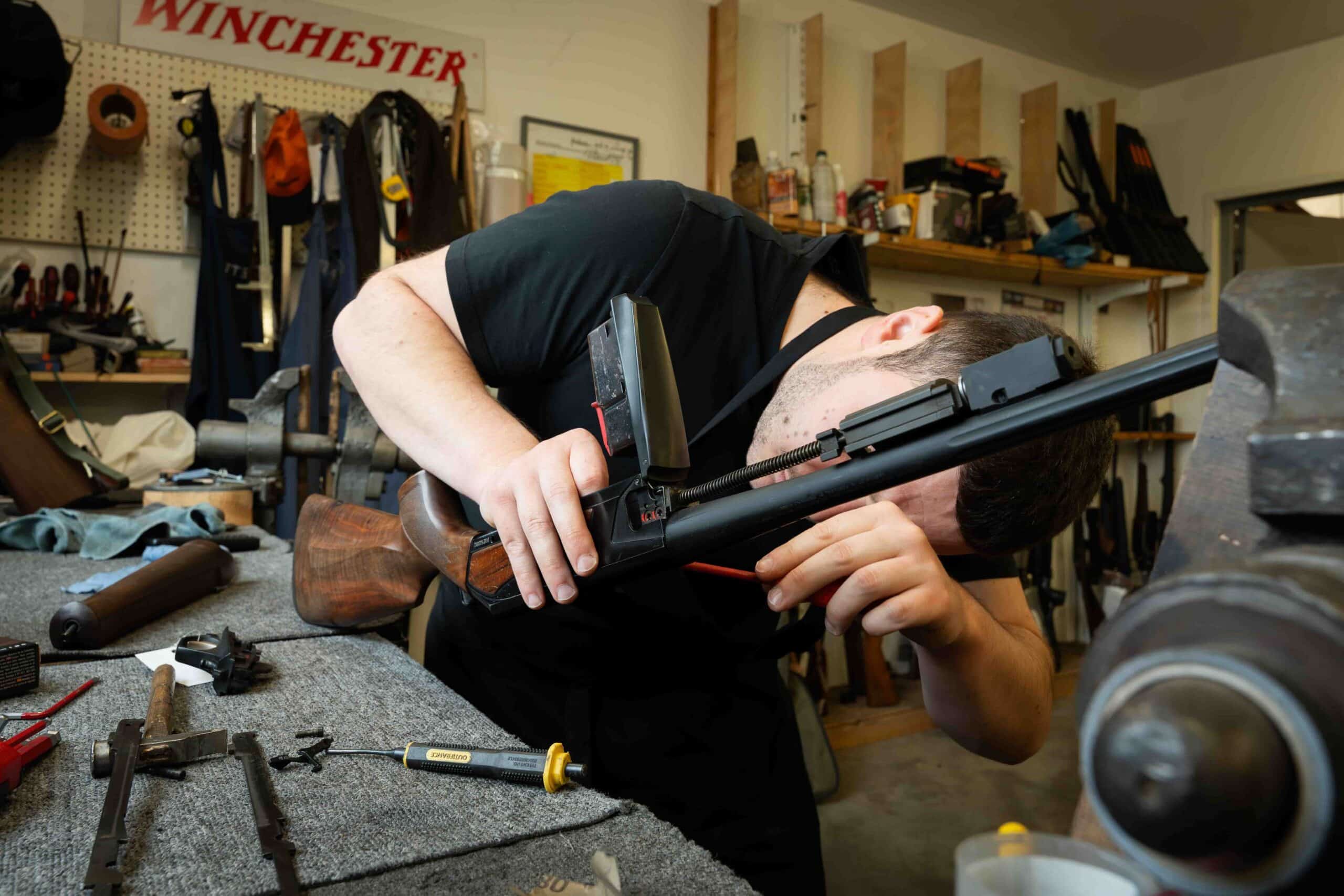 Armurier diplômé travaillant sur le mécanisme de réparation d'une arme